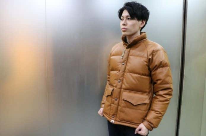 キャメルカラーのダウンジャケットを着た男性