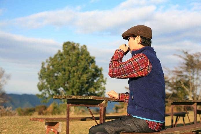 ベンチで温かい飲み物を飲む姿