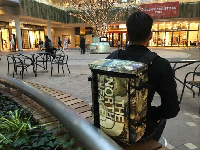 柄モノのノースフェイスのリュックサックを背負った男性