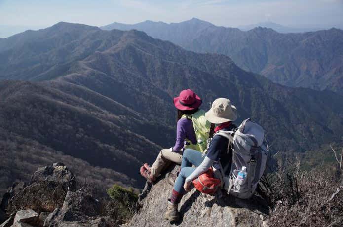 アウトドアの帽子をかぶって登山する人