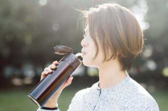 ストロー付きの水筒でドリンクを飲む人