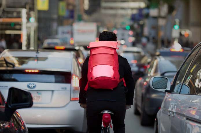ティンバック2の赤いリュックを背負って自転車に乗る男性