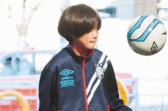 アンブロのウィンドブレーカーでサッカーをする少年