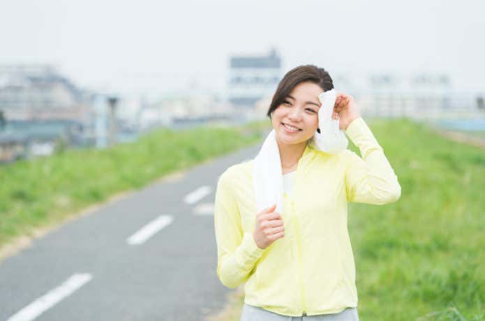 スポーツタオルで汗を拭く女性