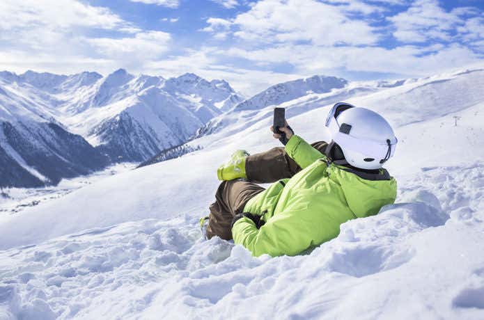 雪山でスマホを使う男性