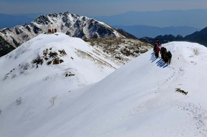 冬の仙丈ヶ岳稜線を行く登山者