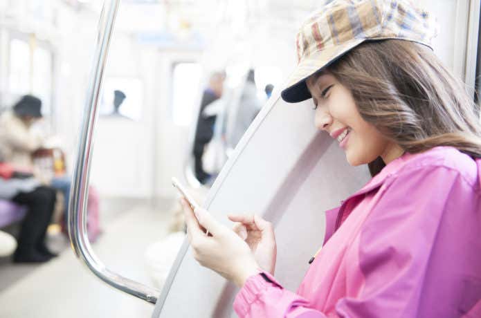 電車でスマホを触る女性