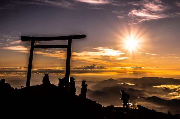富士山の山頂でご来光を見る人