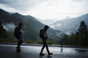 雨の山間を歩く男性2人