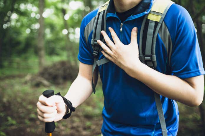 登山中に胸を押さえる男性