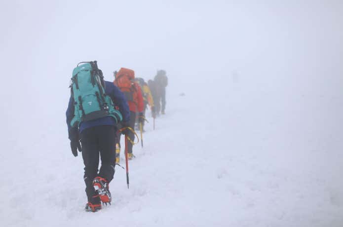 吹雪の中を登山する人