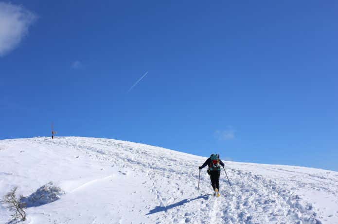 トレッキングポールを使って雪山登る登山者