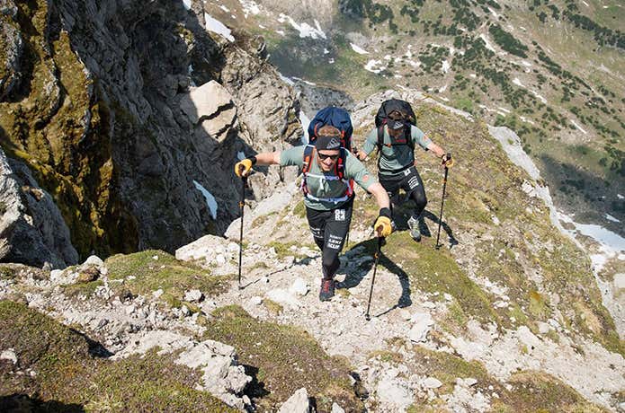 トレッキングポールを使って登山をする男性