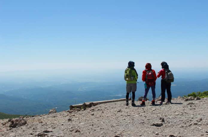 栗駒山山頂から平野を眺める登山客