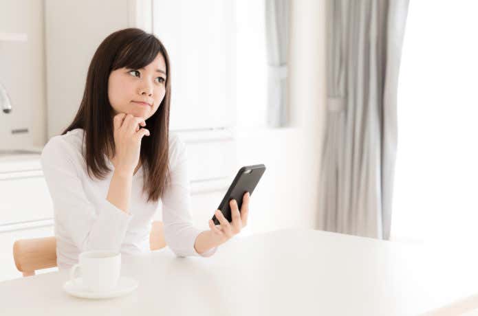 スマホを見て悩む女性