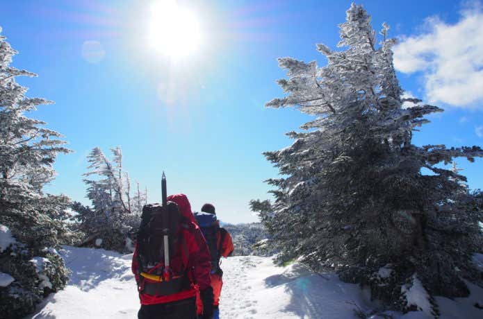 晴天の雪山を歩く登山者