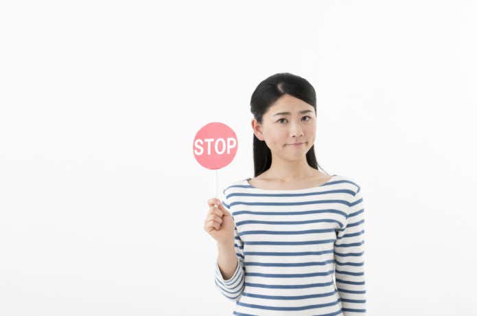 STOPの札を持つ女性