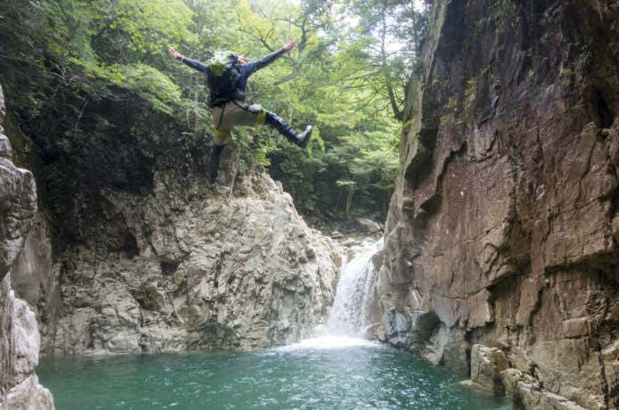 沢登りで滝壷にダイブする男性