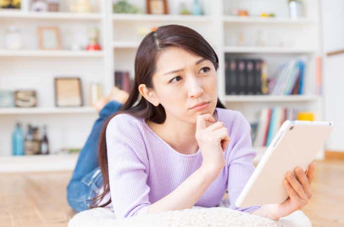 タブレットを見ながら悩む女性