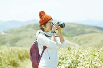 登山道からの景色を写真撮影する登山者