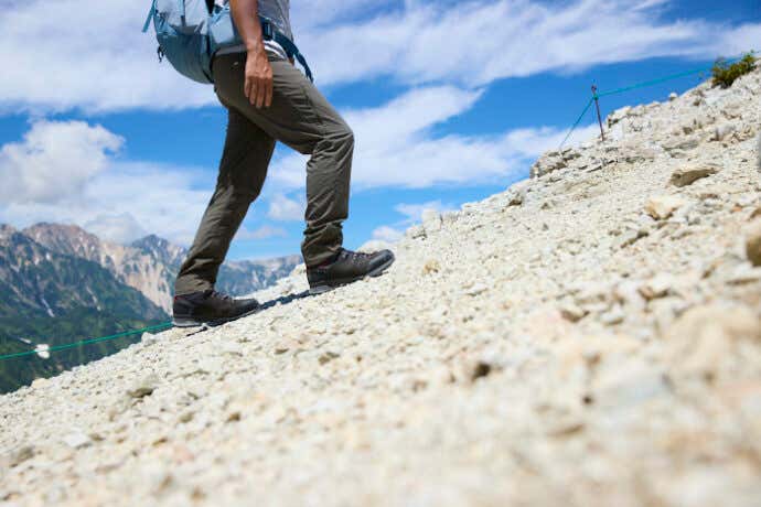 ローバーの登山靴「バルド」で砂礫地の登山道を登る登山者