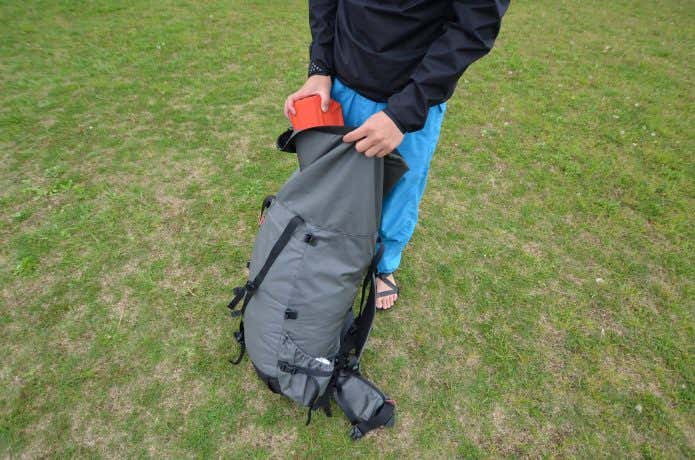 マットをザックに収納する男性