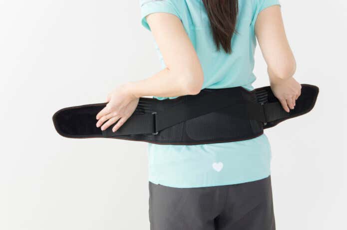 腰痛ベルトを巻こうとする女性