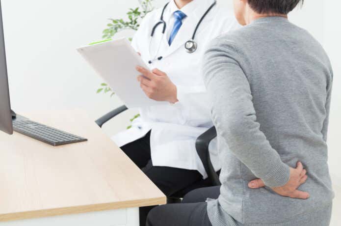 医師に腰痛の診察を受ける人
