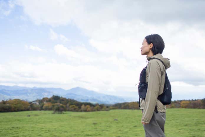 晴天の牧場に立つ女性