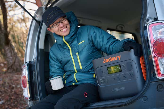 コーヒー片手に満足気にJackery ポータブル電源 2000 Proを触る男性