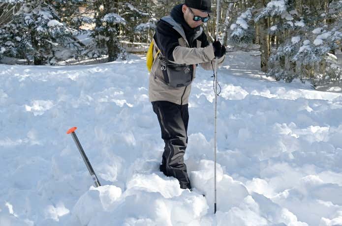 プローブを雪面に刺す人