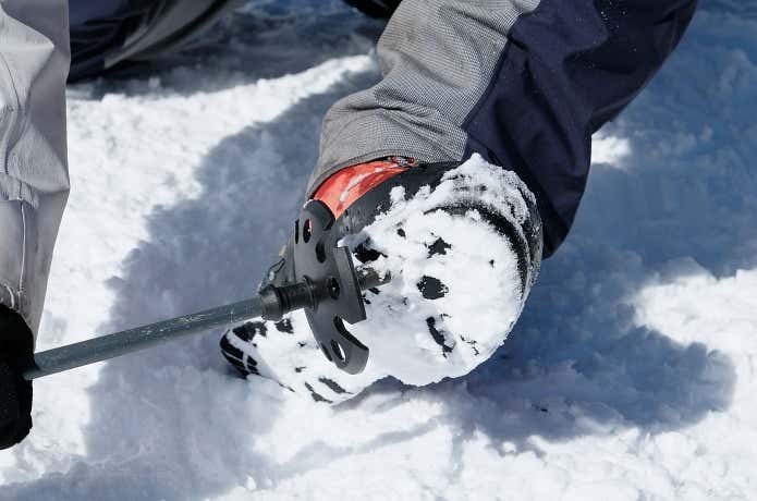 靴底の雪をトレッキングポールを使って落とす