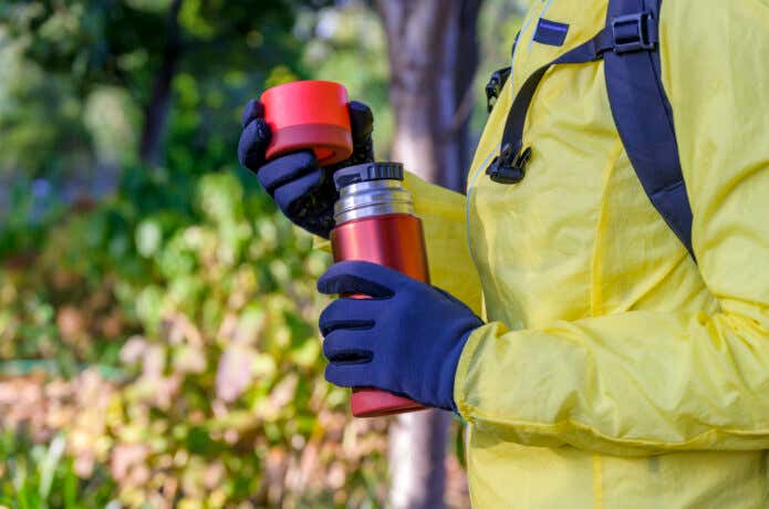 利尿作用のある飲み物を登山中に飲もうとしている様子