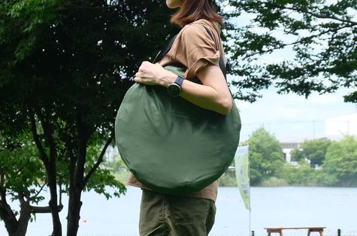 ポップアップテントを収納袋に入れて肩がけしている様子
