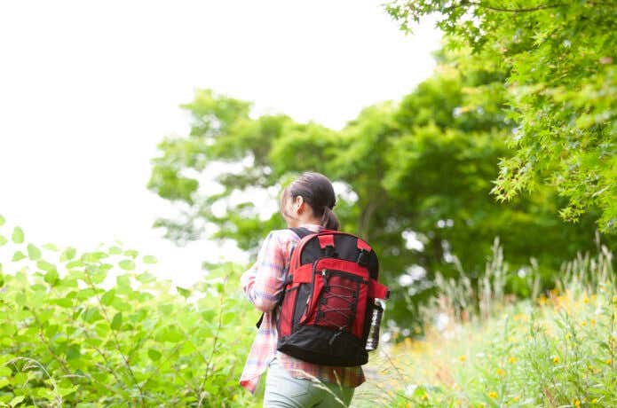 デイパックを背負い山を歩く女性