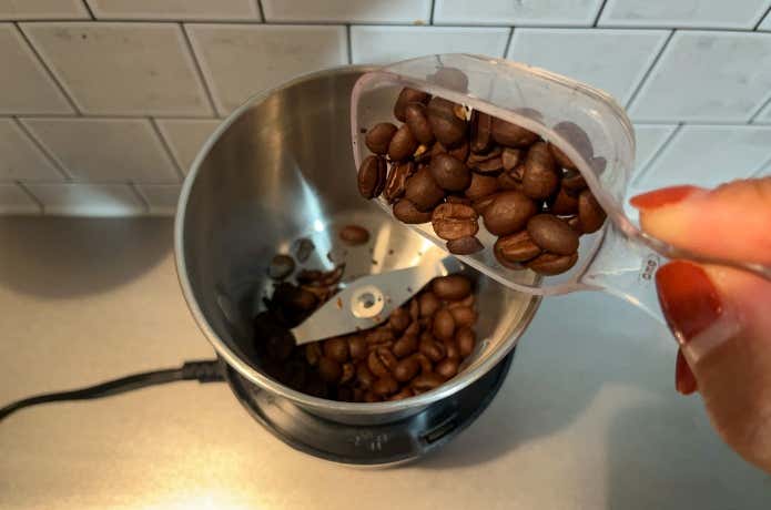 電動ミルにコーヒー豆を入れる様子