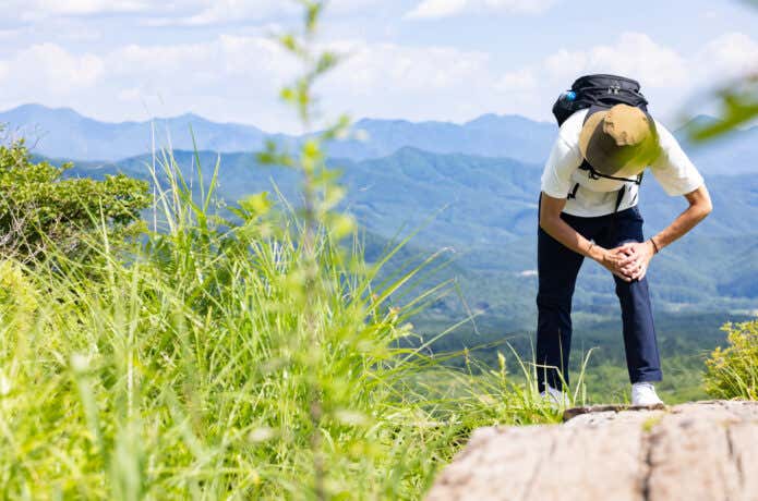 登山中に疲労で膝を抱える人
