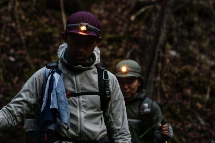 マイルストーンのヘッドランプとキャップを装着して山道を歩く人