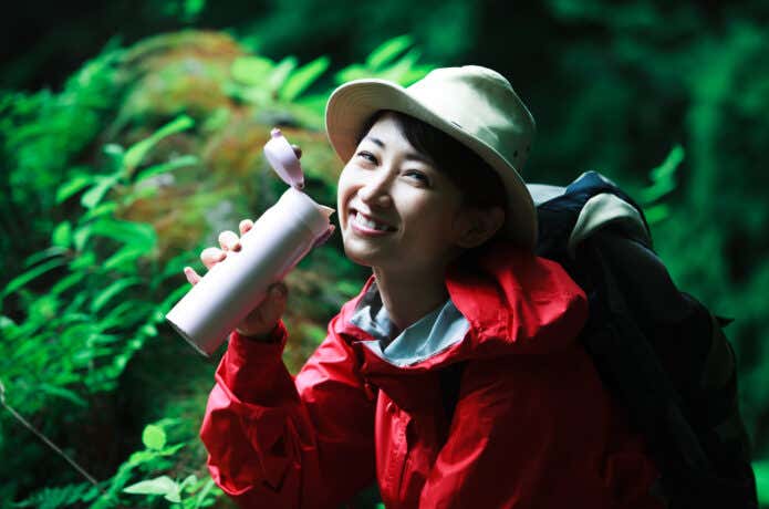登山中に水筒から水を飲もうとする人