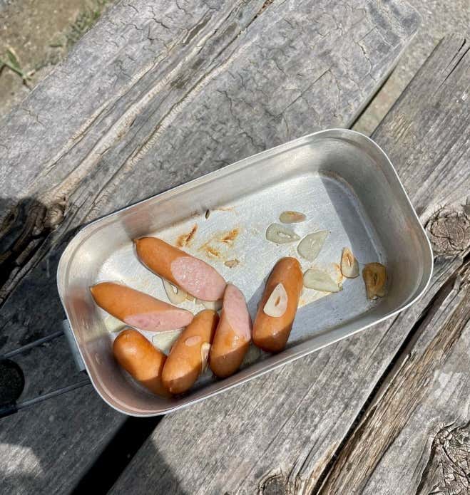 ソーセージ、ニラは食べやすい大きさに切る。にんにく薄切りにする。メスティンに火をかけ、ごま油、にんにく、ソーセージを入れて炒める。