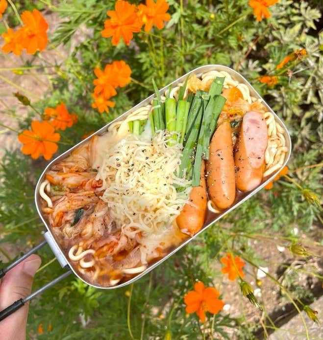 麺に火が通ったら、キムチ、ニラ、チーズをのせて、最後にこしょうをふりかけ出来上がり。