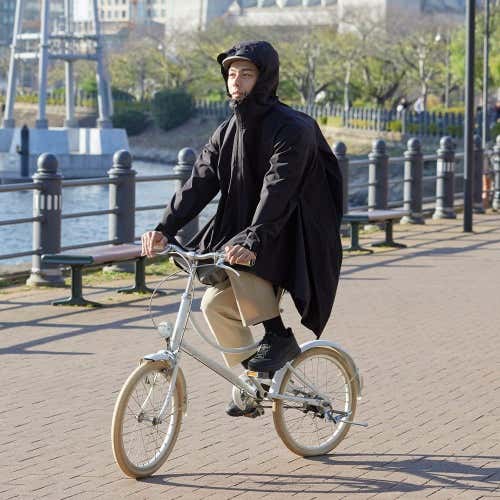 ソロテックス(R)使用バッグイン3WAYロングレインコートを着て自転車に乗る人