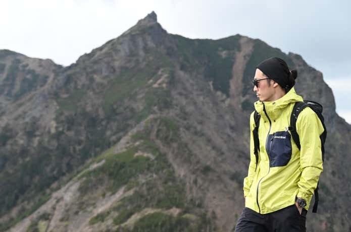 モンベル スーパー ドライテック ピークシェル ジャケット 山を背景に佇む人