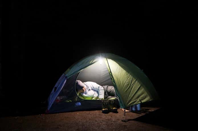夜 テントの中で横になる男性