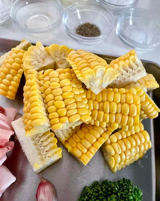 ➀豚肉は食べやすい大きさに切る。とうもろこしは3等分の長さに切る。さらにとうもろこしを立てて、縦に包丁を入れて4つに切り分ける。