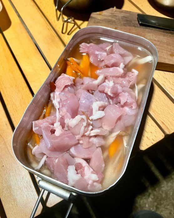 ②メスティンにお米、めんつゆ、しょうゆ、みりんを入れてから、リベット(メスティン内側にある丸ぽち)の真ん中に水を合わせる。合わせてから鶏肉、ごぼう、にんじんを入れる。③蓋をして、固形燃料で25分程度炊飯する。