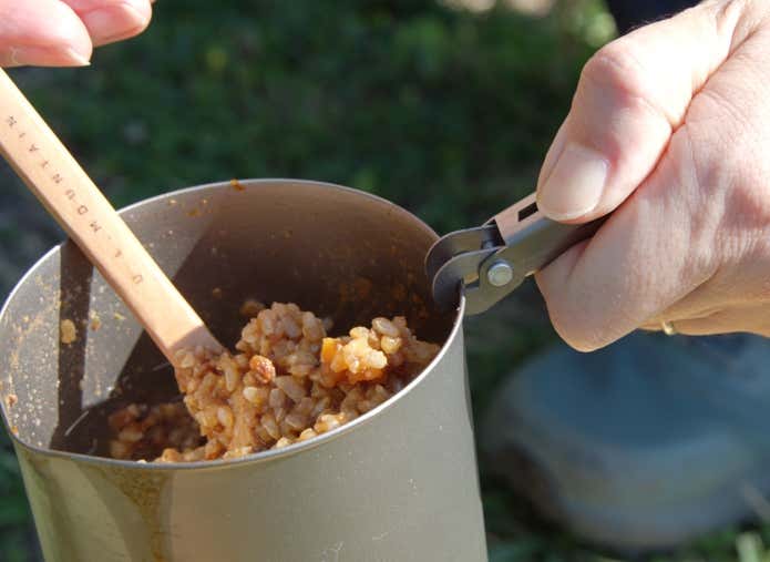 EPIgasのピンチリフターでクッカーを支えたままご飯をかき混ぜる様子