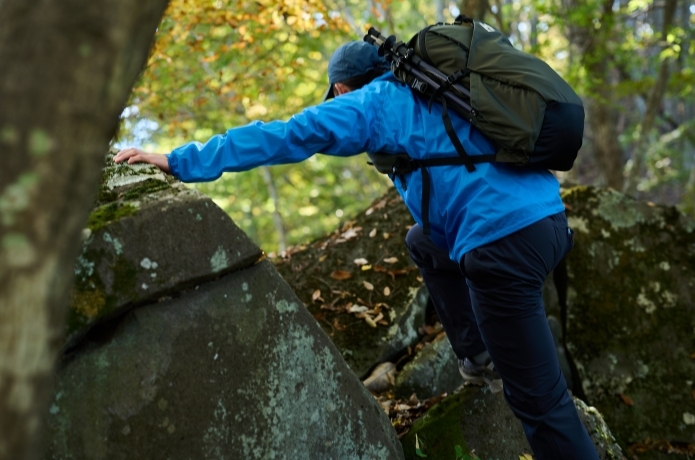 ミレーのレインウェアを着て岩場を登る人