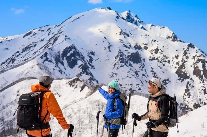 雪の谷川岳を背に談笑する登山者