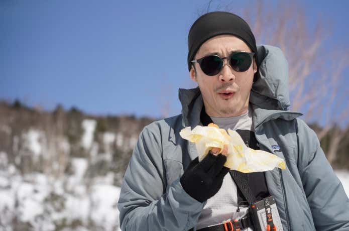 雪山で行動食を補給する人